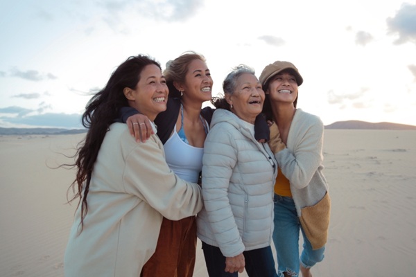 Four women standing on a beach, smiling and looking to the sky