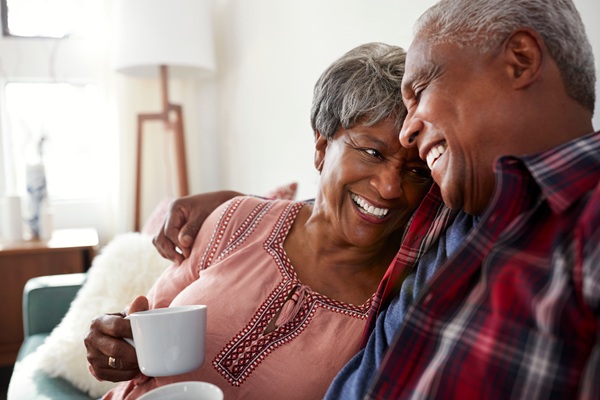 Couple sitting on a couch smiling and drinking coffee