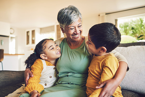 grandma sitting on couch hugging two grandchildren