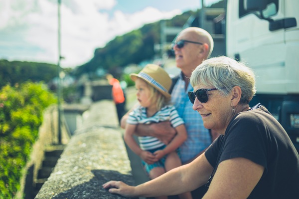 Grandparents with granddaughter stopped at a roadside view point looking out in the distance