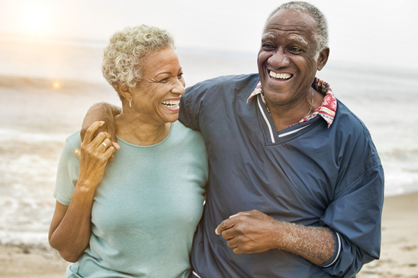 Senior couple embracing while walking on the beach at sunset