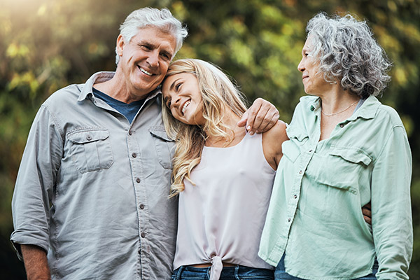Senior parents hugging their daughter and smiling