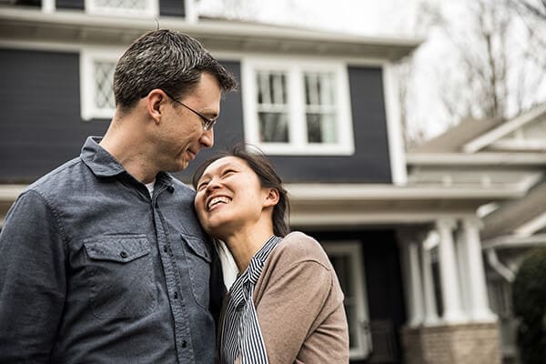 interracial couple standing in front of a house