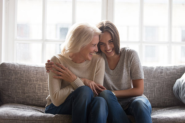 two women embracing and laughing while sitting on a couch