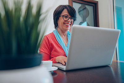 woman smiling while working on a laptop in an office